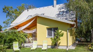 A yellow house with a sloped roof, a small porch with chairs, and a tree in the yard. - Francois by Interhome (Balatonbereny)