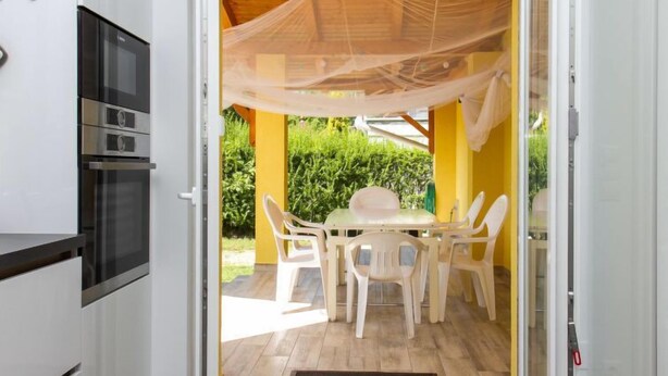 A kitchen with a built-in oven and a dining area with a table and chairs. - Francois by Interhome (Balatonbereny)