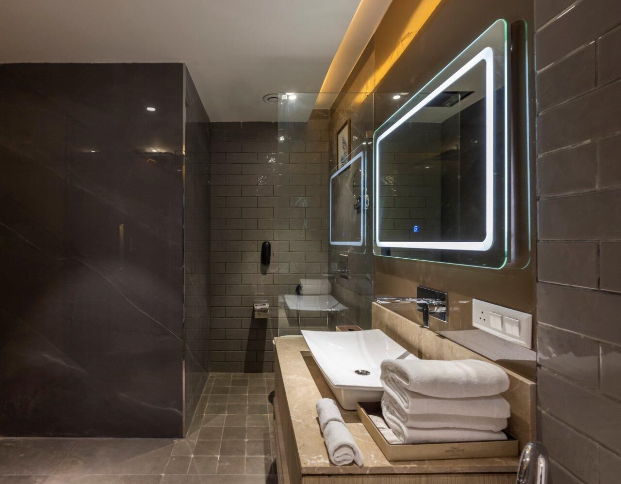 A modern bathroom with a glass-enclosed shower, a vanity with a sink and mirror, and neatly folded towels.