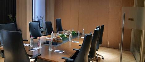 A conference room with a long table, black chairs, water bottles, and a 'PUSH' sign on the door.