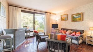 A cozy living room with a sofa, chairs, a TV, and artwork on the wall. - Porto di Mar by Interhome (Cavalaire)