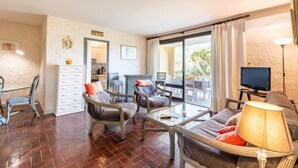 A spacious living area with wicker furniture, a glass coffee table, and a TV. - Porto di Mar by Interhome (Cavalaire)