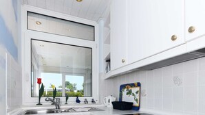 Een moderne keuken met witte kasten, een roestvrijstalen spoelbak en een zwart fornuis.