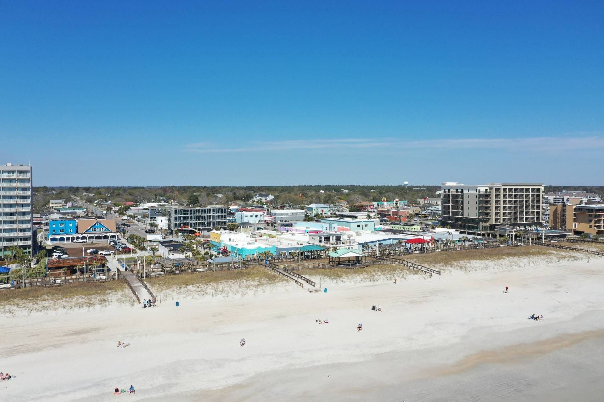 Une ville côtière avec une plage, des bâtiments et un ciel dégagé.