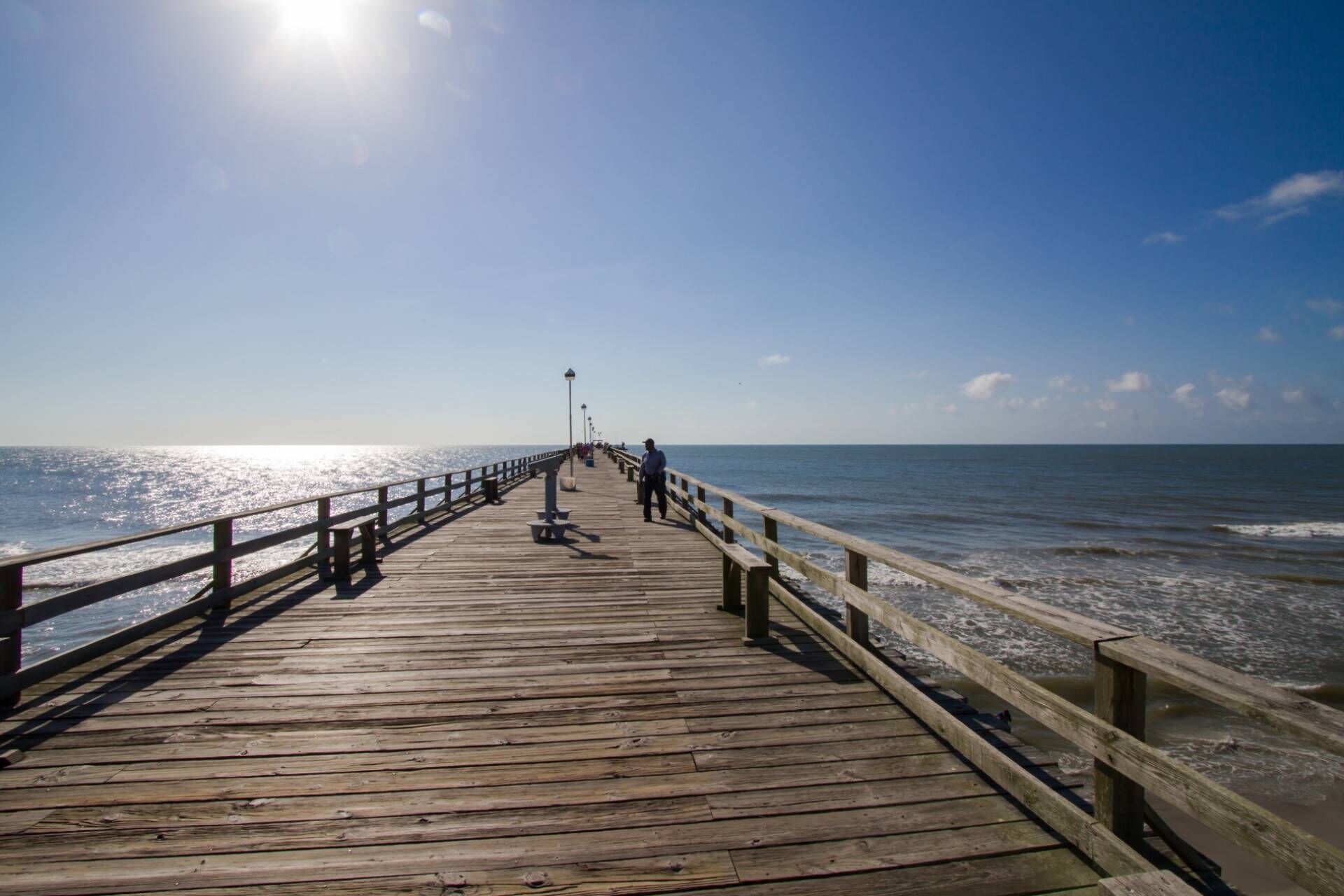A wooden pier extending into the ocean with a clear sky above.