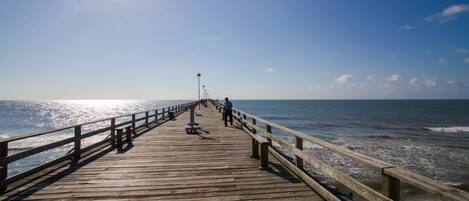 A wooden pier extending into the ocean with a clear sky above.