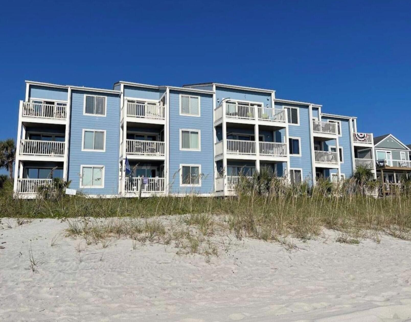 A beachfront multi-story building with balconies, likely a hotel or apartment complex.