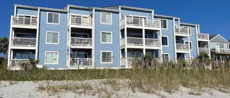 A beachfront multi-story building with balconies, likely a hotel or apartment complex.