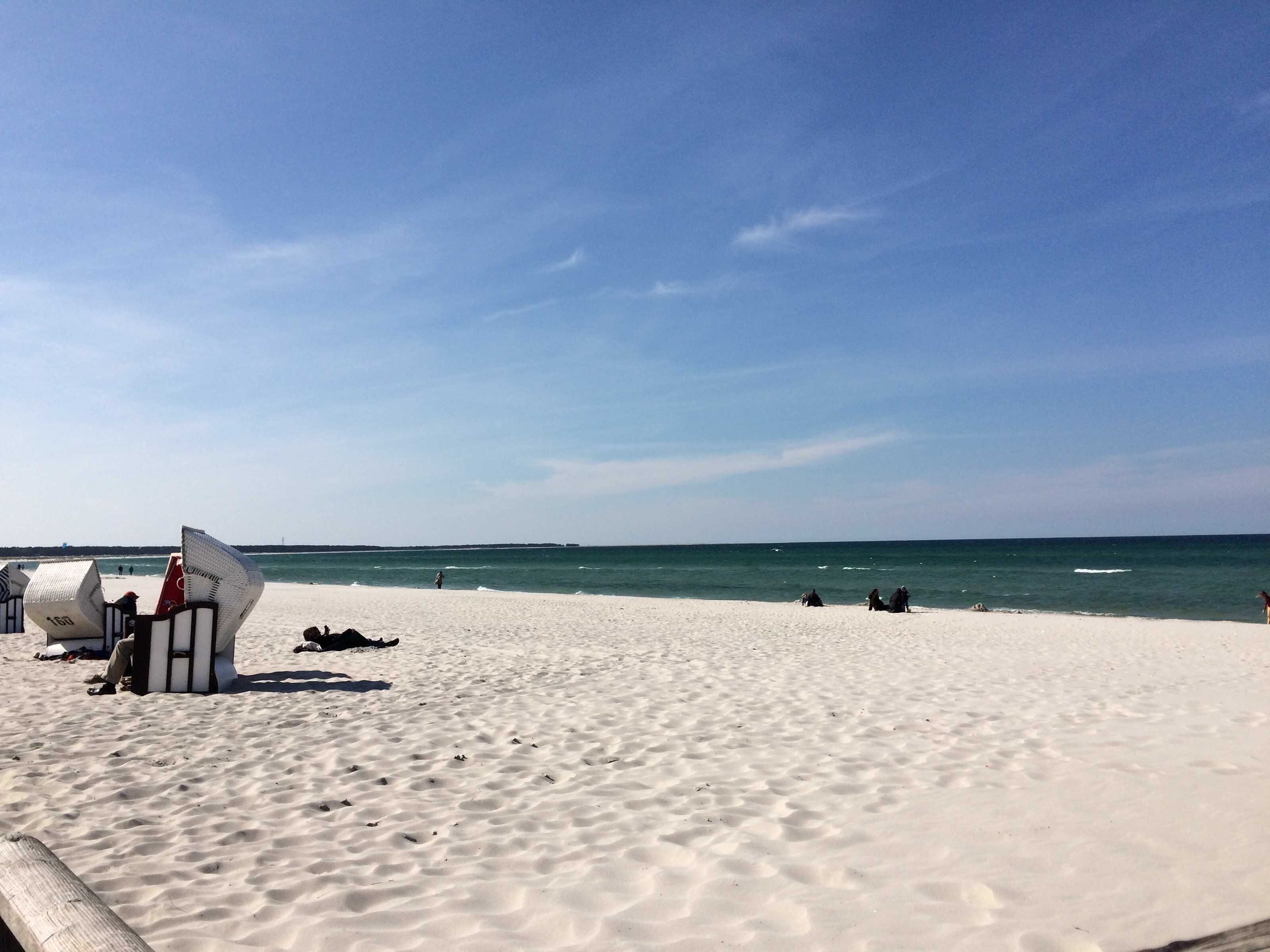 A beach with white sand and the ocean in the background.