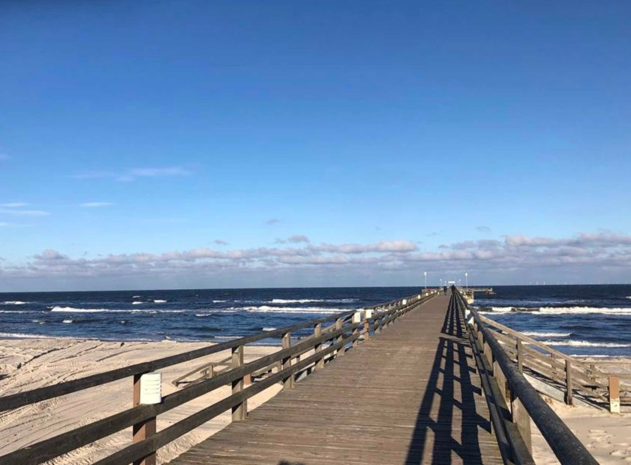 Un muelle de madera que se adentra en el océano bajo un cielo despejado.