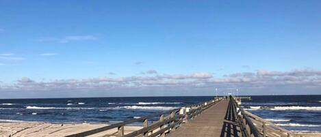 Un muelle de madera que se adentra en el océano bajo un cielo despejado.
