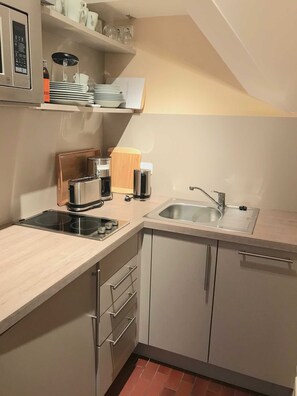 A compact kitchen with a built-in stove, a sink, and a coffee maker. - Ferienwohnung Achterdieck - Haus Borée (Prerow)