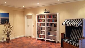 Une pièce avec une bibliothèque, une porte, un petit modèle de bateau et une chaise à rayures.