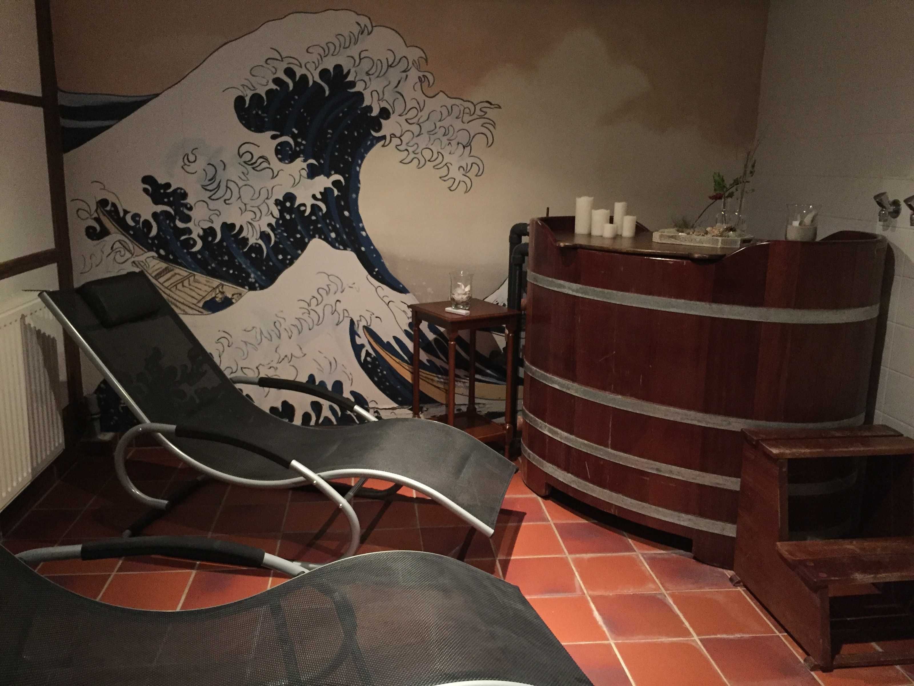 A room with a tatami mat floor, a low wooden table, a chair, and a large Japanese wave painting on the wall.