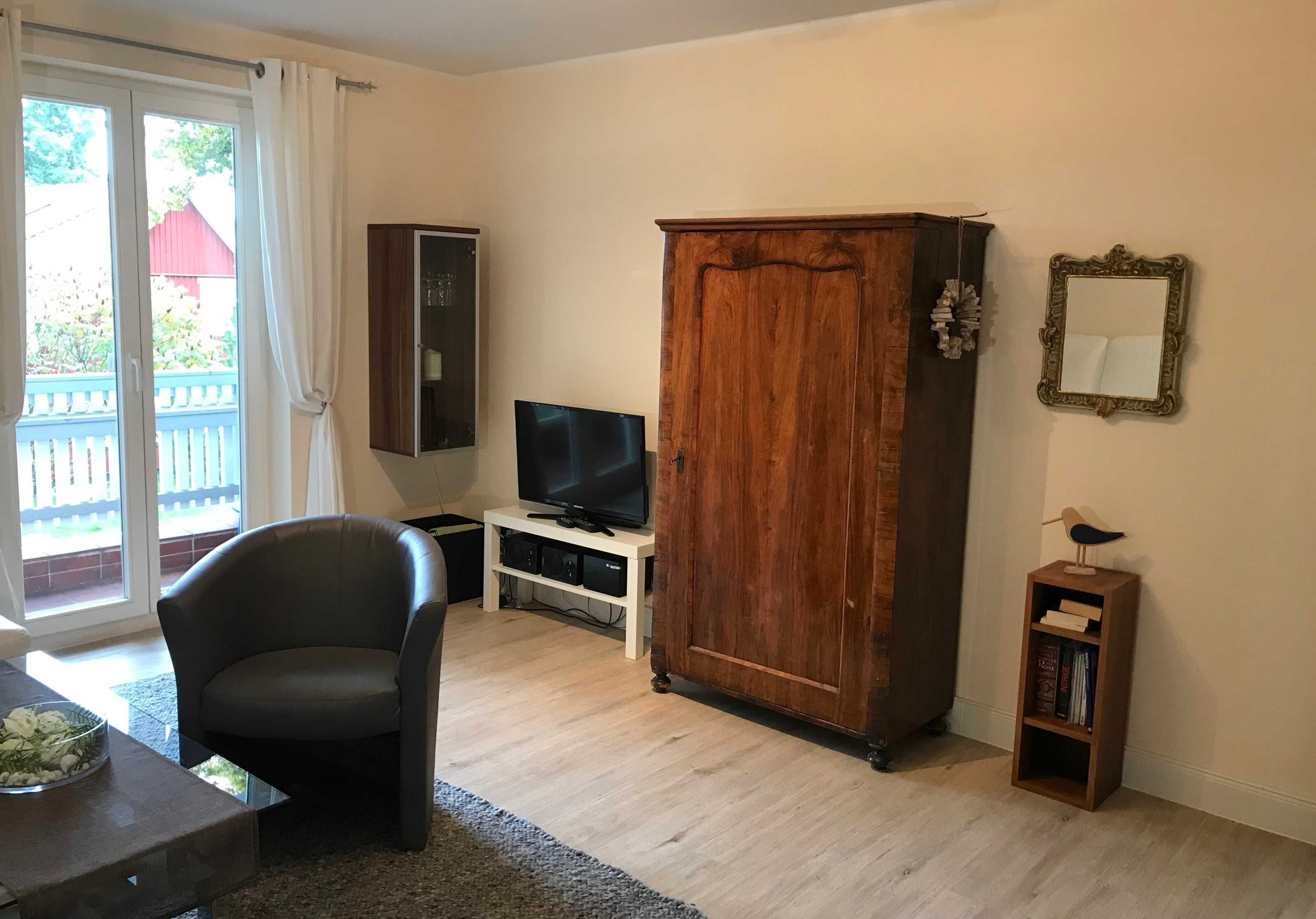 A living room with a television, a large wooden cabinet, a bookshelf, and a chair.