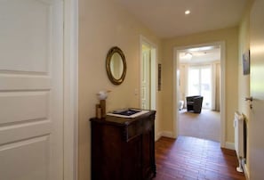 Un couloir avec une armoire en bois, un miroir et une porte donnant sur une autre pièce.