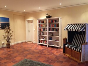 Une pièce avec une bibliothèque, une porte, un petit modèle de bateau et une chaise à rayures.