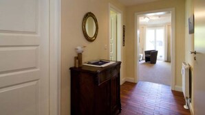 A hallway with a wooden cabinet, a mirror, and a door leading to another room. - Vacation apartment Möövnest - House Borée (Prerow)