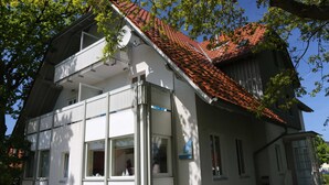 A two-story building with a red-tiled roof, white exterior walls, and a balcony. - Vacation apartment Möövnest - House Borée (Prerow)