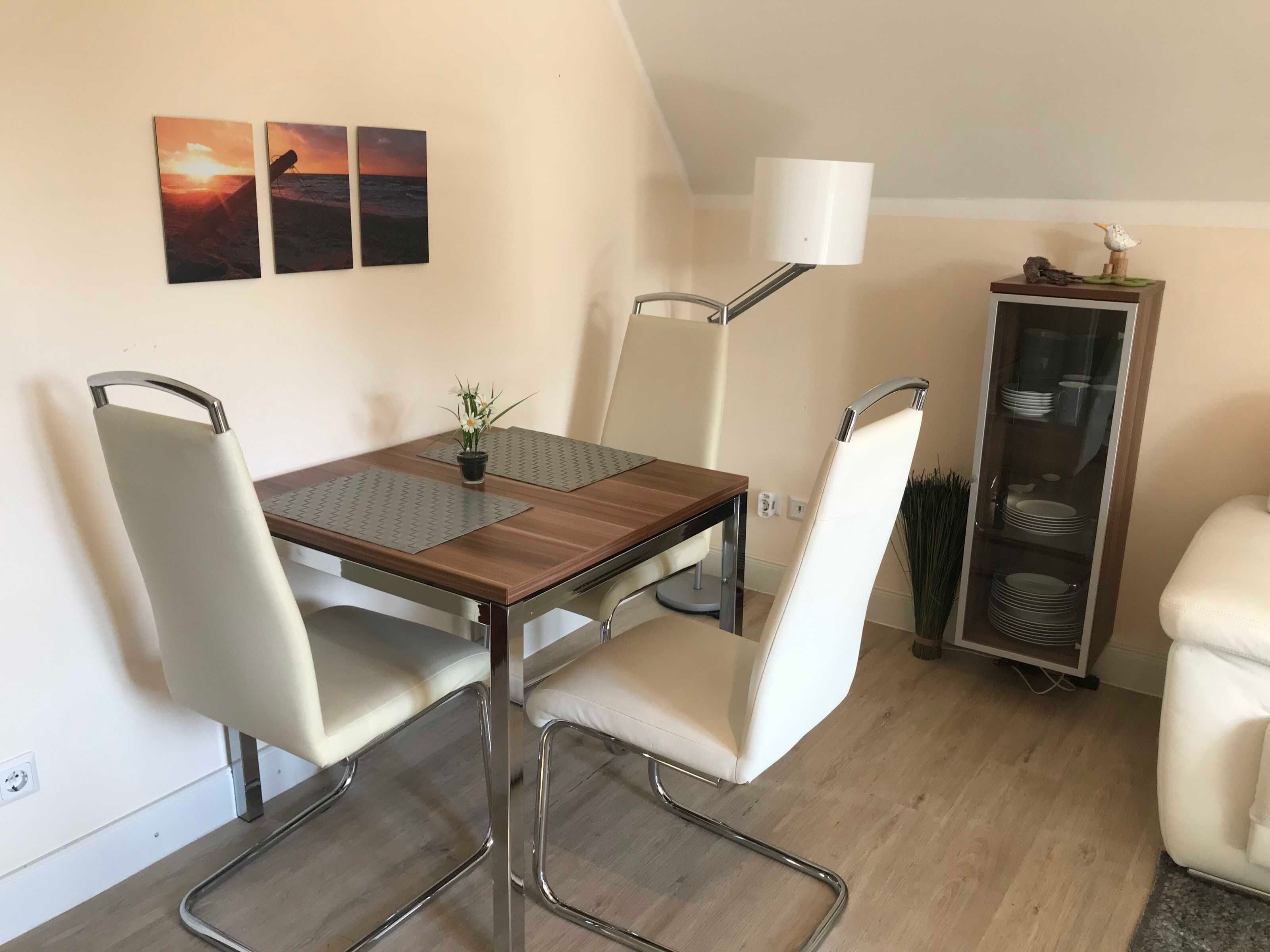 Un comedor con una mesa, sillas, una lámpara y un aparador con vajilla.