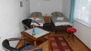 A small, well-lit room with two beds, a desk, a chair, and a window with curtains. - Ferienwohnung Brandt 45042 We27a - Ferienwohnungen Se-br (Sellin)