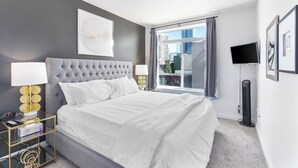 Et moderne hotelværelse med en stor seng, et vindue med udsigt over byen og et fladskærms-tv.