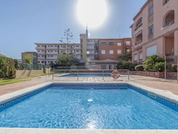 A swimming pool with a lifebuoy, surrounded by a low fence, and buildings in the background. - Torrepuerto by Interhome (Torredembarra)