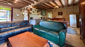 Un intérieur rustique avec un canapé vert, une table basse en bois et des poutres apparentes.