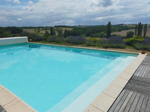 A rectangular swimming pool with a wooden deck surrounding it.