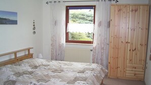 A bedroom with a bed, a window with curtains, a radiator, a wooden wardrobe, and a wall-mounted picture. - Vacation apartment in Seedorf - Holiday apartment Kontschack (Sellin)