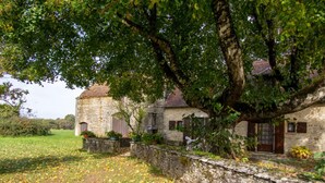 A stone building with a rustic charm, surrounded by a stone wall and lush greenery.