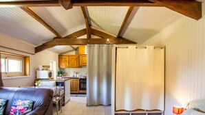 A cozy room with a bed, a leather sofa, and a kitchenette in the background. - Charming studio near Sarlat for a peaceful getaway (La Roque-Gageac)