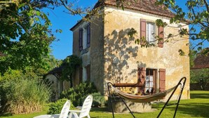 Une maison de campagne en pierre, dotée d’un hamac et d’un espace salon extérieur.