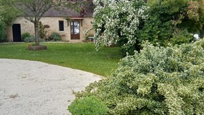 Une maison avec une façade en pierre, une porte d’entrée et une pelouse bien entretenue.