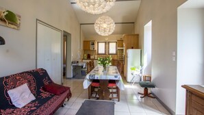 Ein gemütliches Wohnzimmer mit einer Couch, einem Esstisch und einer Küche im Hintergrund.