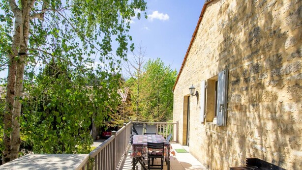 Ein Steinhaus mit Balkon, Tisch und Grill.