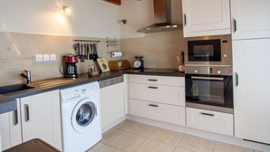 Una cocina compacta con lavadora, microondas y estufa.