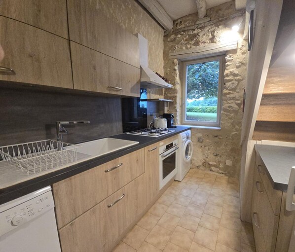 A compact kitchen with a stone wall, a window with a view, and modern appliances.