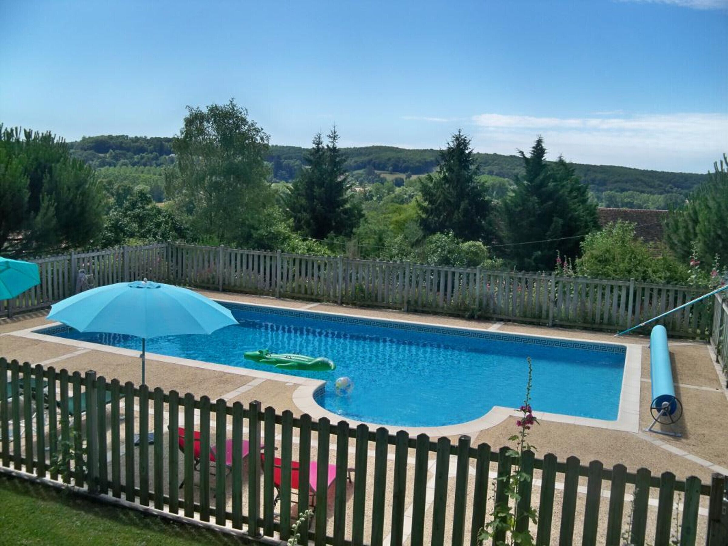 Une piscine rectangulaire bordée de bleu, entourée d’une clôture en bois.