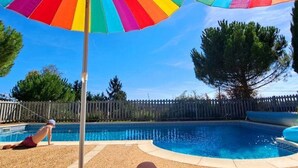 A swimming pool with a wooden fence and a tree in the background.