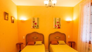 A room with two beds, a chandelier, and artwork on the walls.