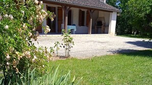 A house with a covered porch, a brick fireplace, and a gravel driveway.
