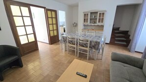 A living room with a dining table, two sofas, a coffee table, and a kitchen area with cabinets and a fan. - Charming house in Domme with WiFi near the Dordogne (Domme)