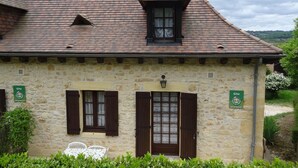 A stone building with a tiled roof, two windows with shutters, and a small porch area. - Charming house in Domme with WiFi near the Dordogne (Domme)