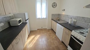 A compact kitchen with a microwave, stove, sink, and dishwasher. - Charming house in Domme with WiFi near the Dordogne (Domme)