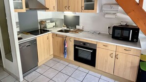 A compact kitchen with wooden cabinets, a built-in oven, a microwave, and a toaster.