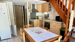 A compact kitchen with wooden cabinets, a microwave, and a dining table with chairs.