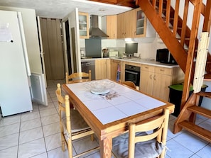 Uma cozinha compacta com armários de madeira, micro-ondas e uma mesa de jantar com cadeiras.