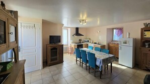 A compact kitchen with a dining area, a TV, and a refrigerator. - Charming Countryside Retreat with Fireplace, Garden, and Family Amenities in Tourtoirac, France (Tourtoirac)