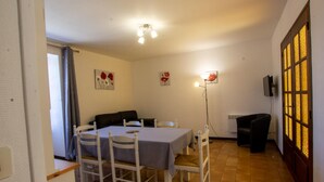 A dining area with a table and chairs, a sofa, and a wall-mounted TV. - Charming house near Domme with Wifi, 2 bedrooms (Domme)